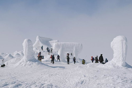 冬の刈田岳山頂に立つ登山者たちと雪の造形物