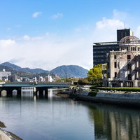 青空の下、元安川に映る原爆ドーム、橋と川面の反射の写真