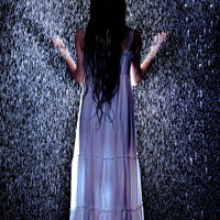 ゲリラ豪雨に打たれる白いワンピース姿の女性の後姿の写真