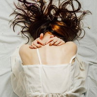 床に蹲る女性モデルの後ろ姿、絶望的な心理状態を表現の写真