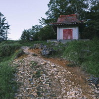 金精峠の赤い扉がついた白い社、登山道の石積み上に建つ山岳信仰の拠点の写真