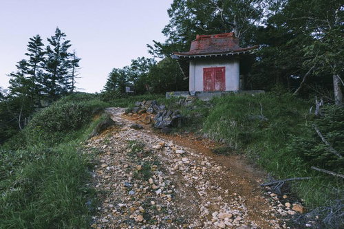 金精峠の赤い扉がついた白い社、登山道の石積み上に建つ山岳信仰の拠点