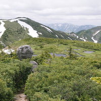 平ヶ岳山頂の玉子石と残雪が残る山並み、高山の稜線風景の写真