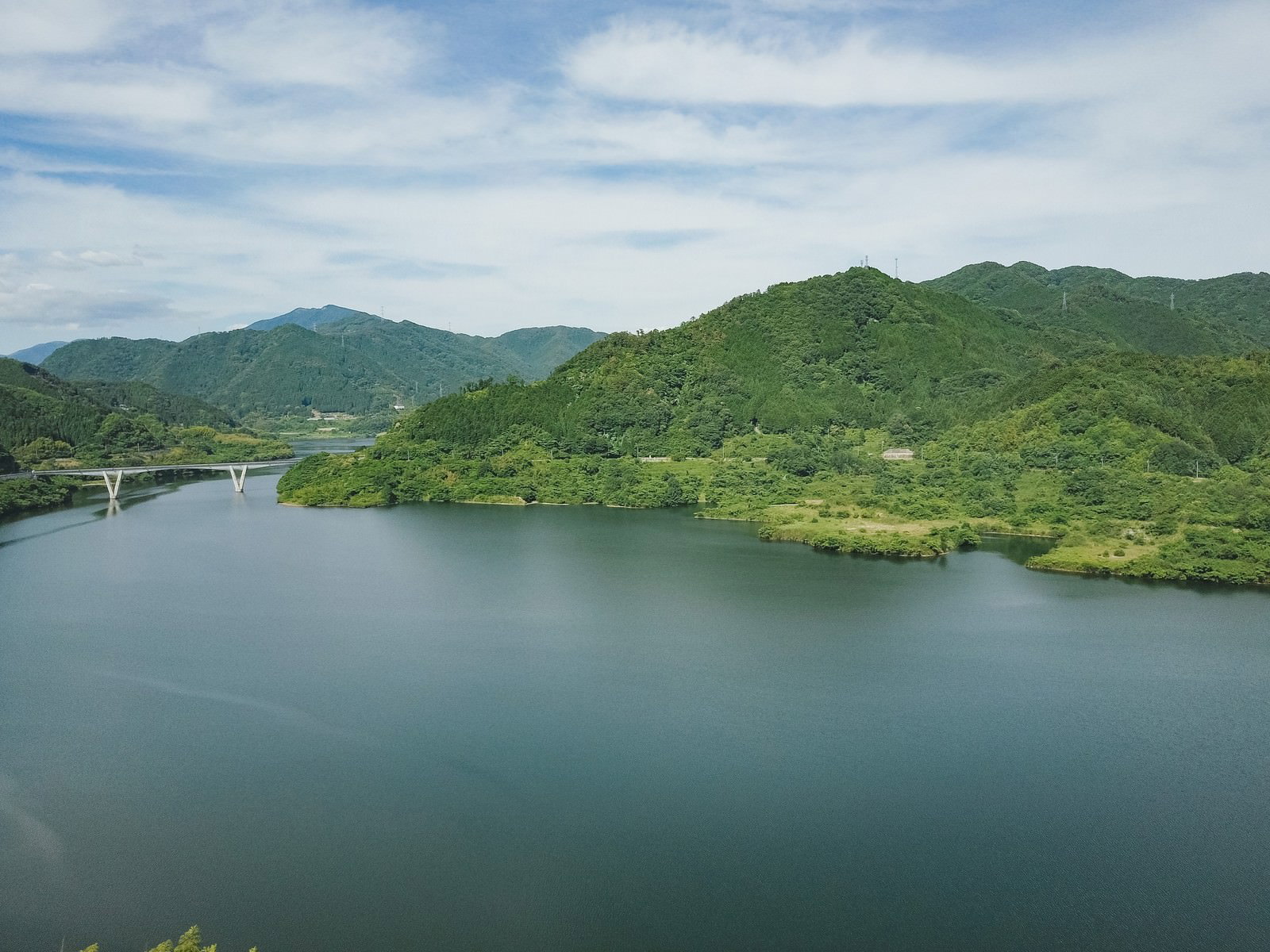 青空の下、緑豊かな山々に囲まれた奥津湖の風景