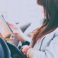 くつろぎながらスマホをいじる女性の横顔、室内でリラックスの写真
