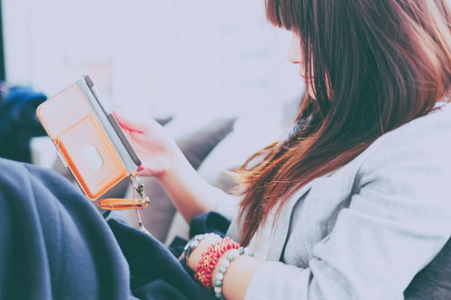 くつろぎながらスマホをいじる女性の横顔、室内でリラックス