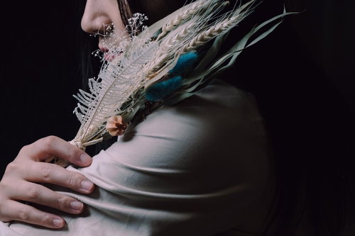 ドライフラワーのスワッグを肩に寄せる女性の横顔