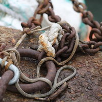 船着き場の桟橋に置かれた錆びた鎖とロープの写真