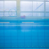 プールサイドの青い水面と屋内プール施設の清潔な空間の写真