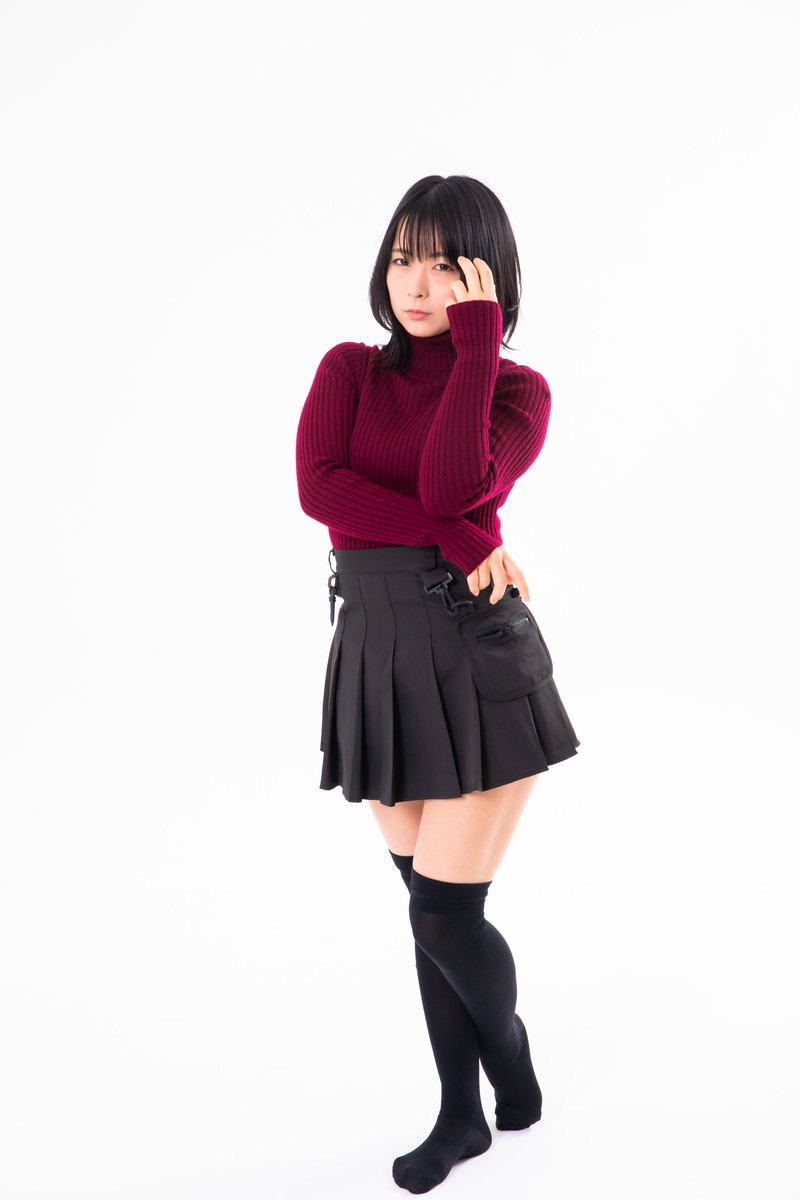えんじ色のニットと黒いスカートを着た女性が顎に手を当てて考え込むポーズ［モデル：にゃるる］