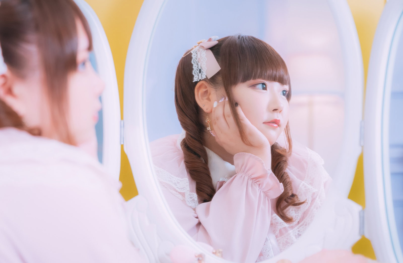 レースのヘアクリップとツインテール姿で、鏡の中で歯痛ポーズをする女の子［モデル：あづき］