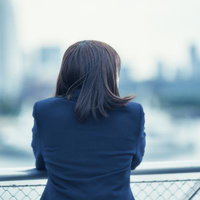 街並みを眺める女子高生の後ろ姿と都市風景の写真