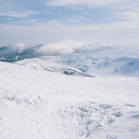 雪に覆われた蔵王の稜線と周辺の山々の冬山風景の写真