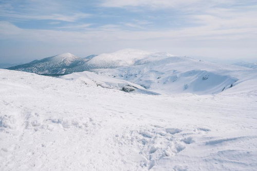 雪に覆われた蔵王の稜線と周辺の山々の冬山風景
