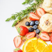 まな板に並べたカットフルーツとスコーンの朝食の写真