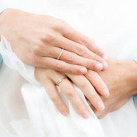 結婚指輪をはめた新郎新婦の手の写真
