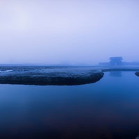 霧に包まれた古代遺跡の石造建築と水辺の歴史的景観の写真