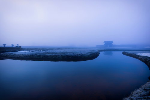 霧に包まれた古代遺跡の石造建築と水辺の歴史的景観