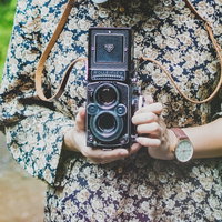 花柄の服を着たレトロなフィルムカメラを持った女性の写真