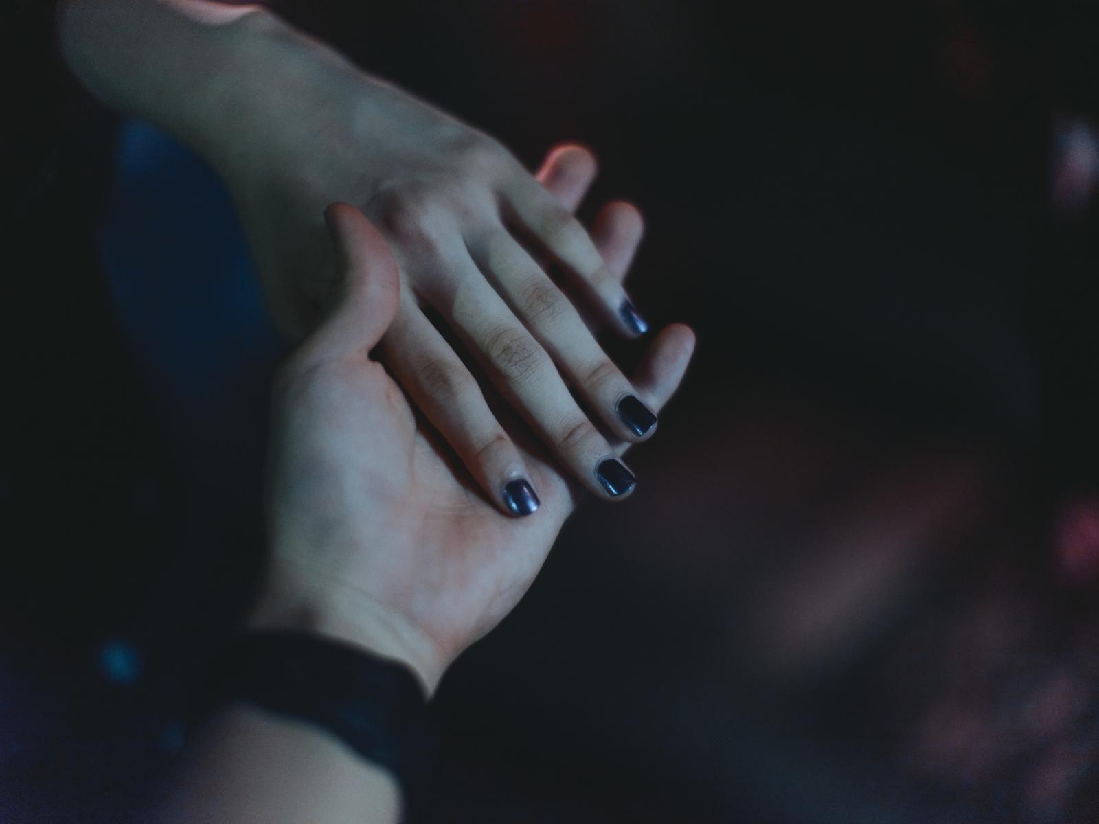暗闇で二人の手が握り合い、互いに絆で結ばれている場面