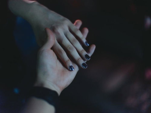 暗闇で交わす二人の手に映る絆と親密なふれあい