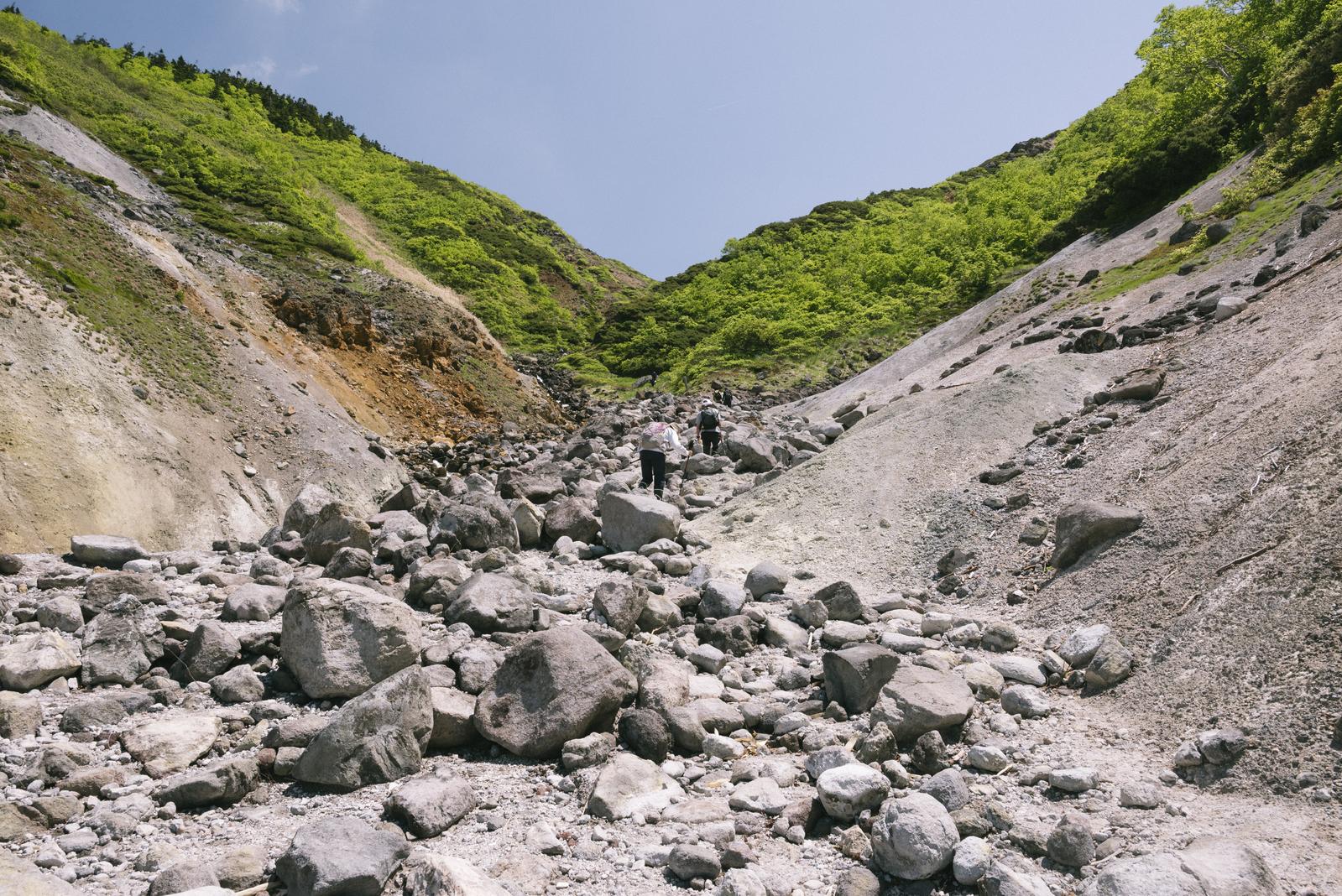 八甲田山の地獄谷で岩場を歩む登山者たちの様子