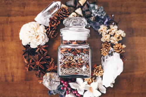 木製テーブルに散らばったドライハーブに囲まれた小瓶