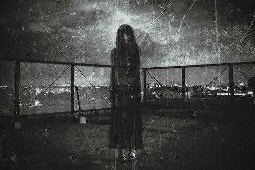 屋上フェンス越しに立つゴースト女性のシルエット