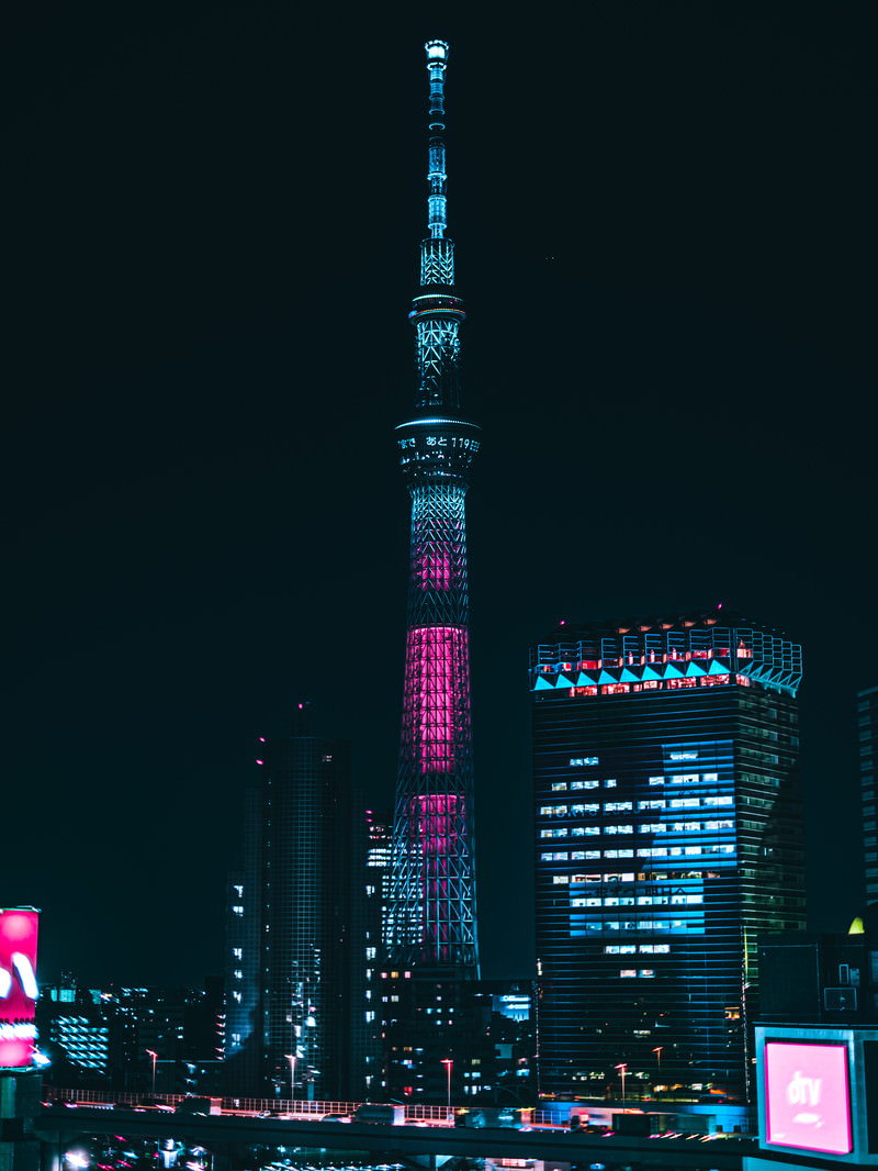 夜空に青紫色にライトアップされた東京スカイツリーと色とりどりに照らされた高層ビル群