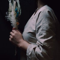 造花のフラワーバンドルを手にして祈る女性の写真