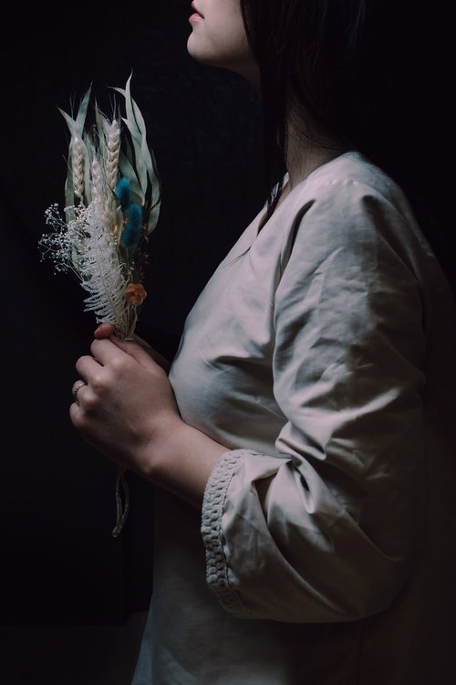 造花のフラワーバンドルを手にして祈る女性