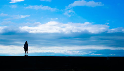 目の前に広がる青空と女性の後ろ姿のシルエット