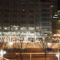 夜間に進む建設工事中のマンション、街灯に照らされた建設現場の写真