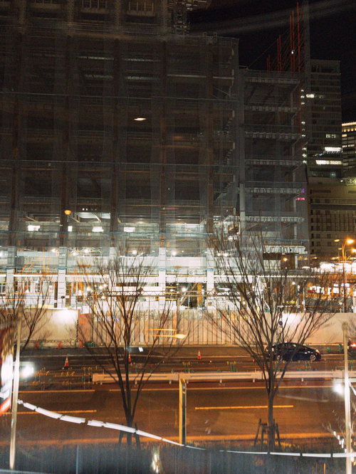 夜間に進む建設工事中のマンション、街灯に照らされた建設現場