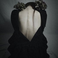 前屈みでうなだれるベアバックの女性の後ろ姿の写真