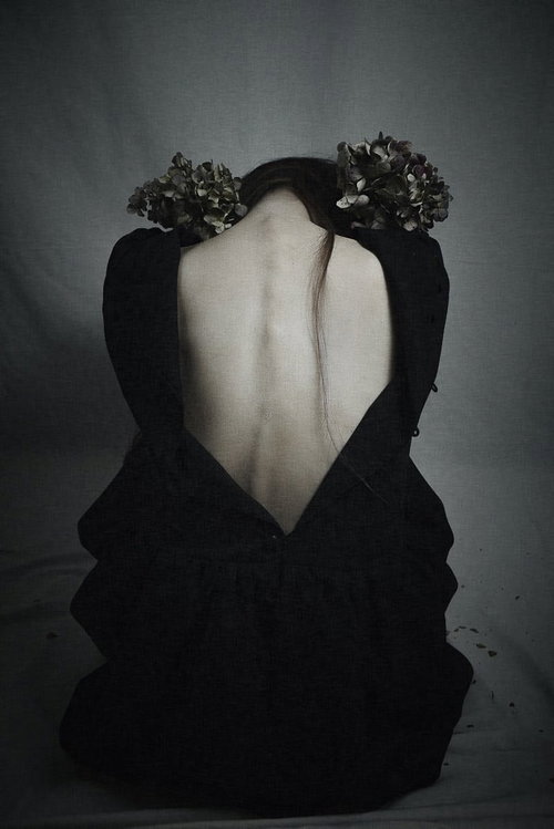 前屈みでうなだれるベアバックの女性の後ろ姿