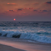 与論島の夕焼けに染まる砂浜と波打ち際の海岸風景の写真