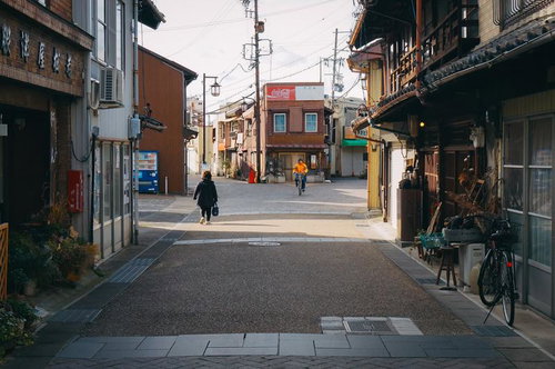 下町の古い住宅街を抜ける通り、電柱と看板のある昭和レトロな町並み