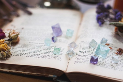 古書の上に置かれた紫と青のフローライト結晶