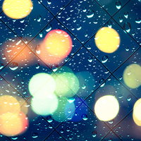 ネオンの光が映る窓の水滴の写真