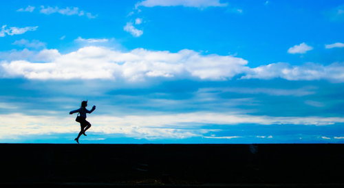 気分は上々でスキップする女性のシルエット