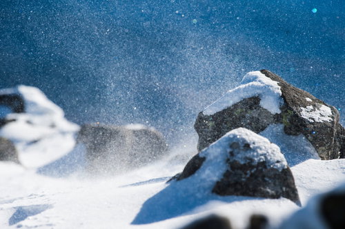 厳冬期の蓼科山で舞い上がる雪の粒子と岩場の風景