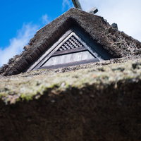 茅葺屋根の古民家と青空の写真