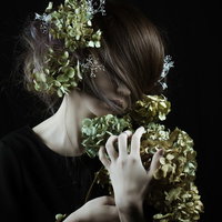 モスグリーンの髪飾りを手に持つ女性の横顔ポーズの写真