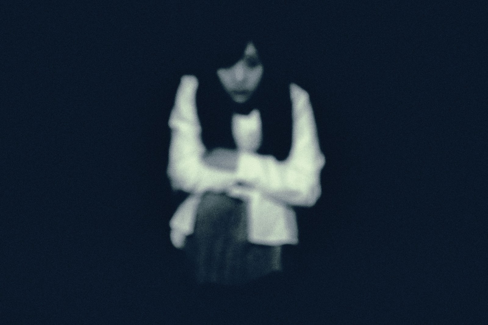 暗闇の中でこちらを見つめている女性が座り込んでいる