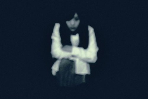 暗闇からこちらを見つめる女性の顔、恐怖表現