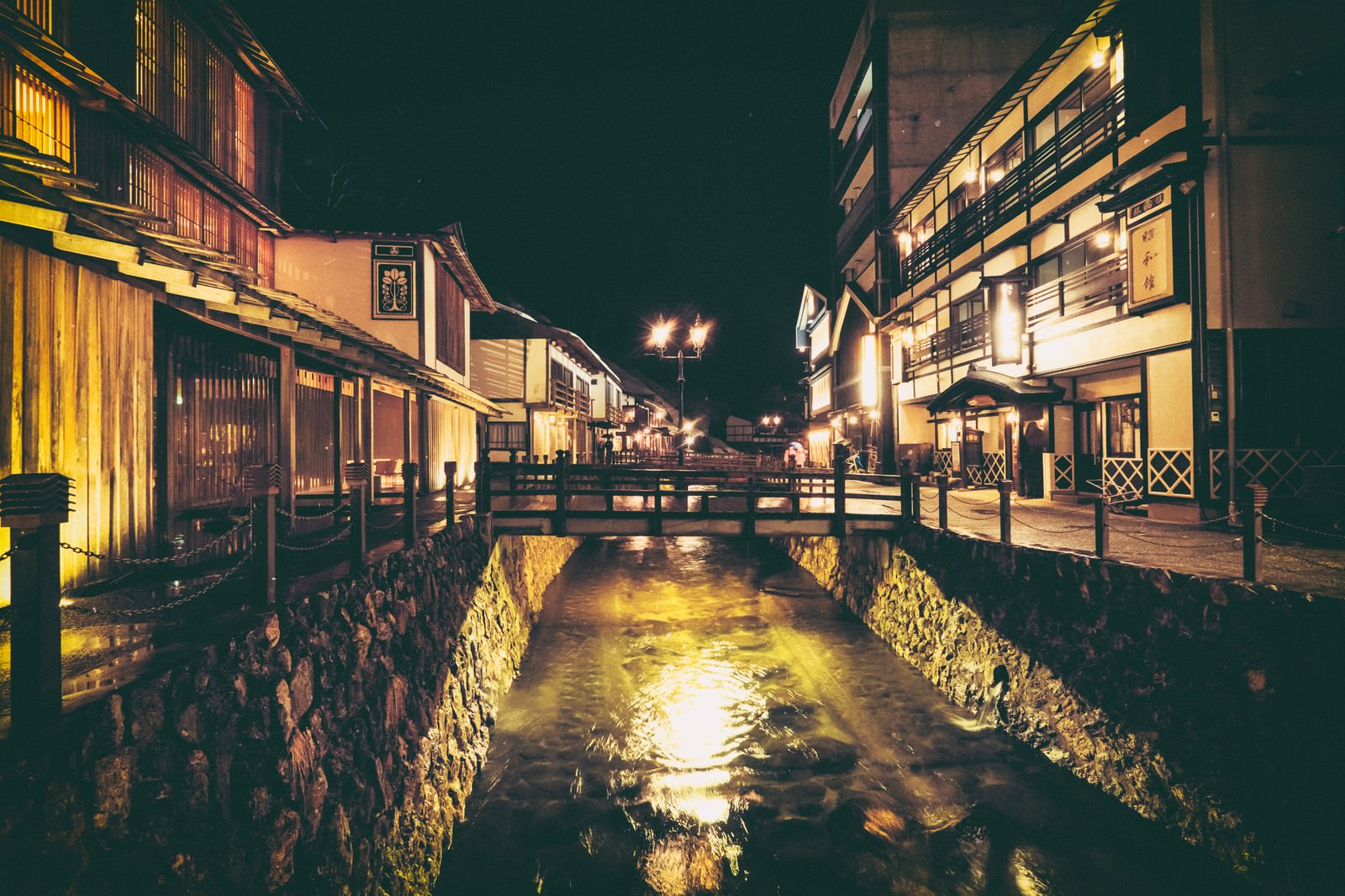 夜の銀山温泉街、川沿いに建つ旅館群とガス灯が灯る温泉街の風景