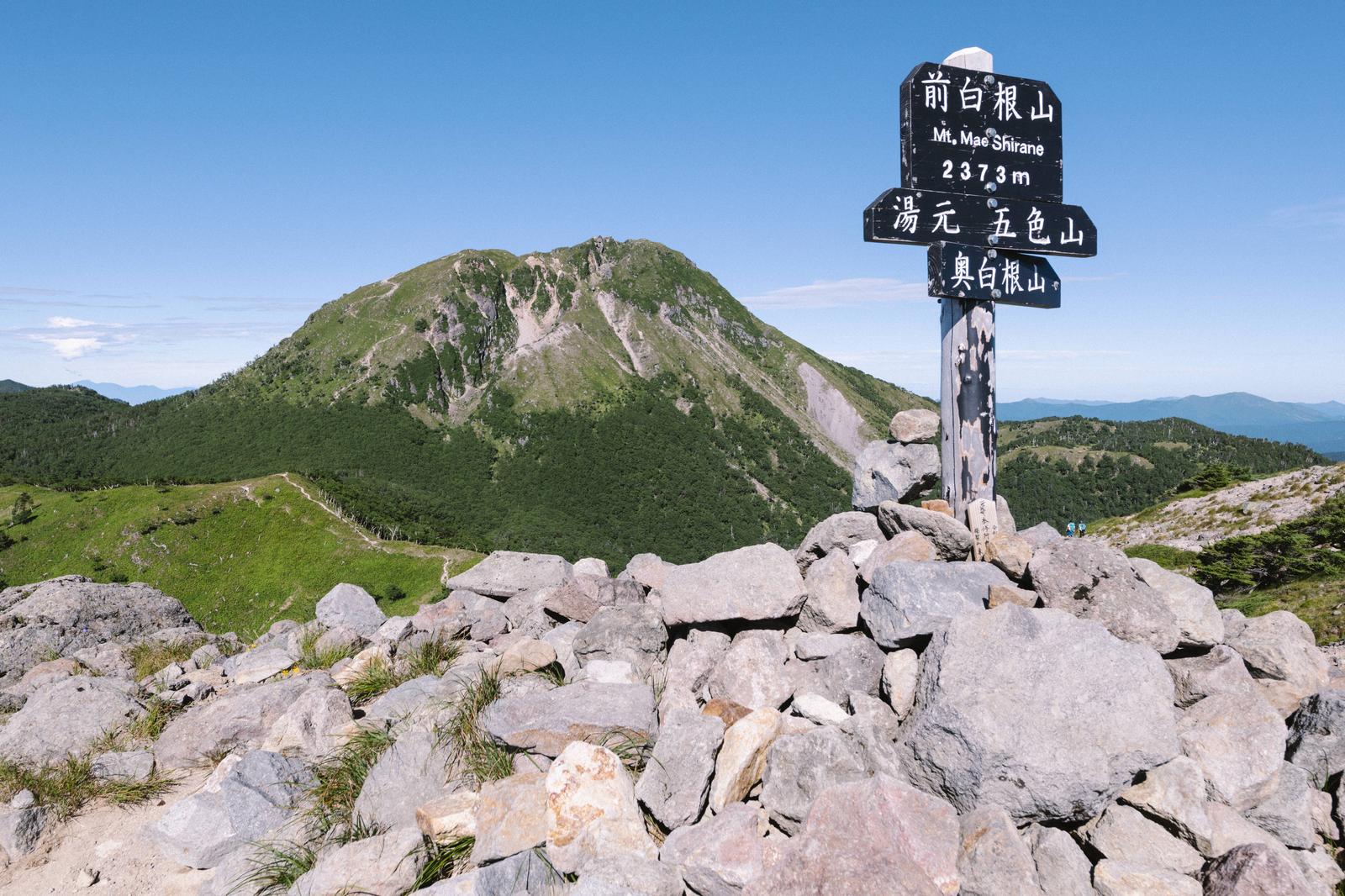 前白根山の山頂に立つ指導標と背景に見える白根山の景観