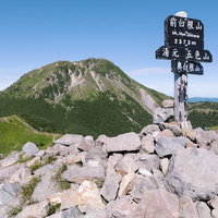 前白根山の山頂からそびえる白根山と指導標の写真