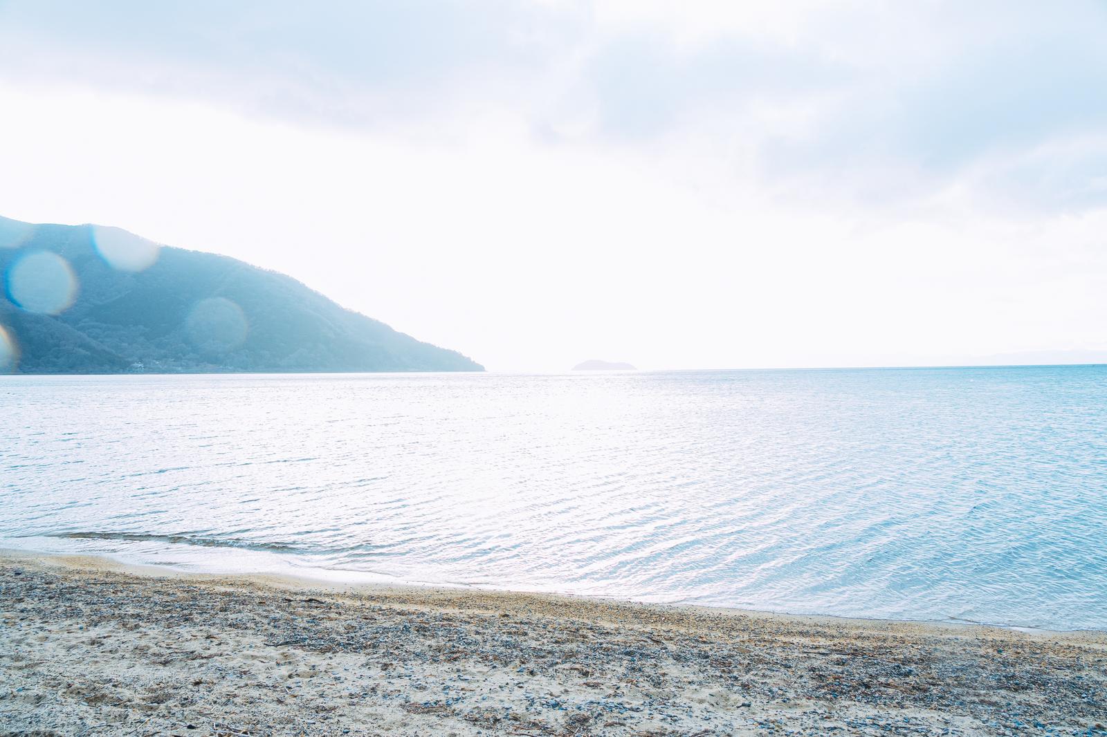 朝日が映る琵琶湖と霞む湖畔の山並みの風景